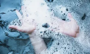 Mains douces dans un spa qui mousse, créant des bulles apaisantes.