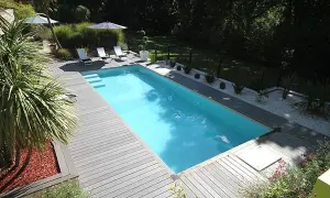 Piscine avec terrasse en bois, transats et parasols. Le **dosage sel piscine** est essentiel pour une eau claire et saine.