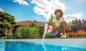 Femme versant du sel dans une piscine, assurant le bon temps de dissolution du sel pour une eau cristalline.