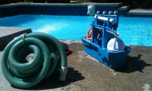 Kit d'entretien piscine pour les nuls : tuyau vert enroulé et boîte bleue avec accessoires de nettoyage.