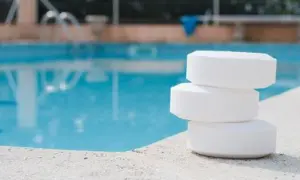 Trois pastilles de chlore empilées sur le bord d'une piscine. Le stabilisateur ppm est trop bas, il faut agir vite !