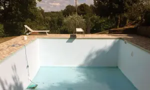 Une piscine hors sol presque vide, avec un tuyau bleu et un aspirateur au fond. Idéal pour apprendre comment vider une piscine hors sol.