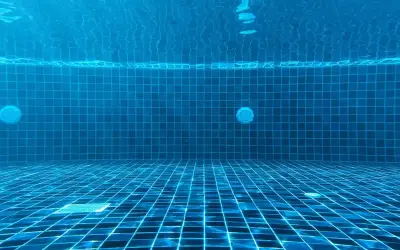 Vue sous-marine d'une piscine carrelée de bleu. La lumière du soleil filtre à travers l'eau. Question : chlore choc combien de temps faire tourner la pompe ?