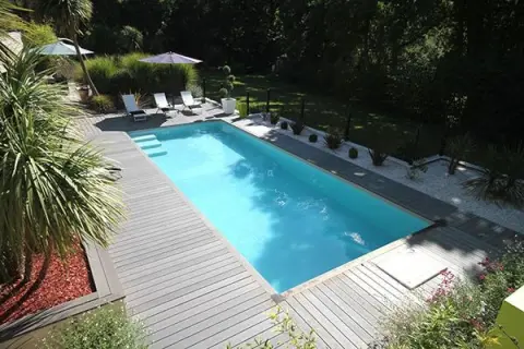 Piscine avec terrasse en bois, transats et parasols. Le **dosage sel piscine** est essentiel pour une eau claire et saine.