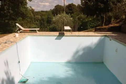 Une piscine hors sol presque vide, avec un tuyau bleu et un aspirateur au fond. Idéal pour apprendre comment vider une piscine hors sol.
