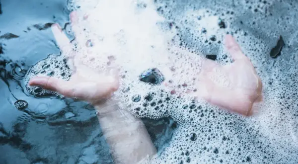 Mains douces dans un spa qui mousse, créant des bulles apaisantes.