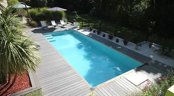 Piscine avec terrasse en bois, transats et parasols. Le **dosage sel piscine** est essentiel pour une eau claire et saine.
