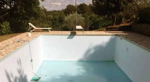 Une piscine hors sol presque vide, avec un tuyau bleu et un aspirateur au fond. Idéal pour apprendre comment vider une piscine hors sol.