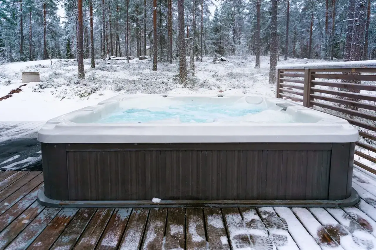 Un jacuzzi fumant dans un paysage enneigé, un parfait spa hivernal pour se réchauffer au milieu des pins.