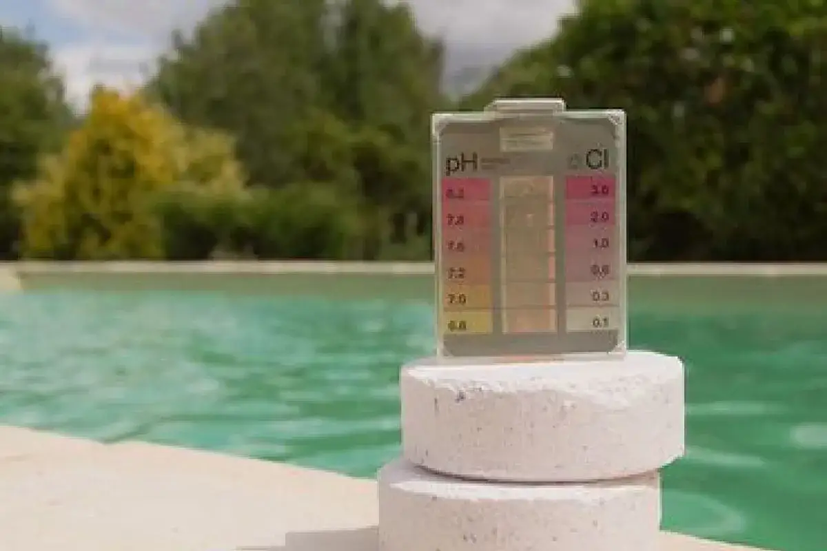 Testeur de pH et de chlore posé sur des pastilles, prêt à vérifier la qualité de l'eau de la piscine.