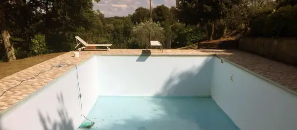 Une piscine hors sol presque vide, avec un tuyau bleu et un aspirateur au fond. Idéal pour apprendre comment vider une piscine hors sol.